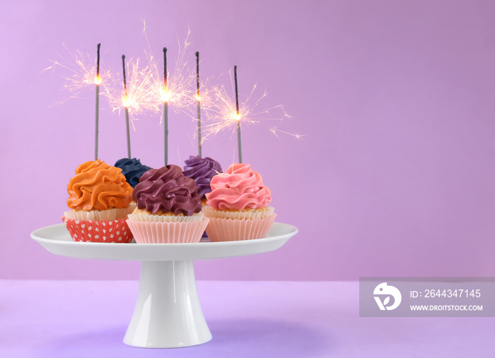 Stand with tasty birthday cupcakes on color background