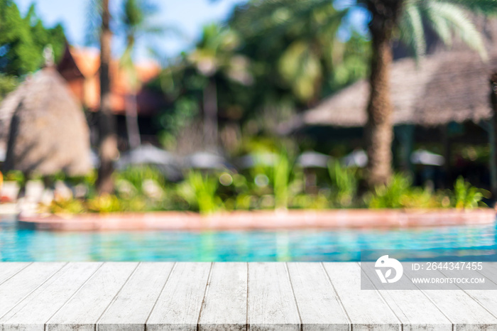 Empty wood table top and blurred swimming pool in tropical resort in summer banner background - can used for display or montage your products.