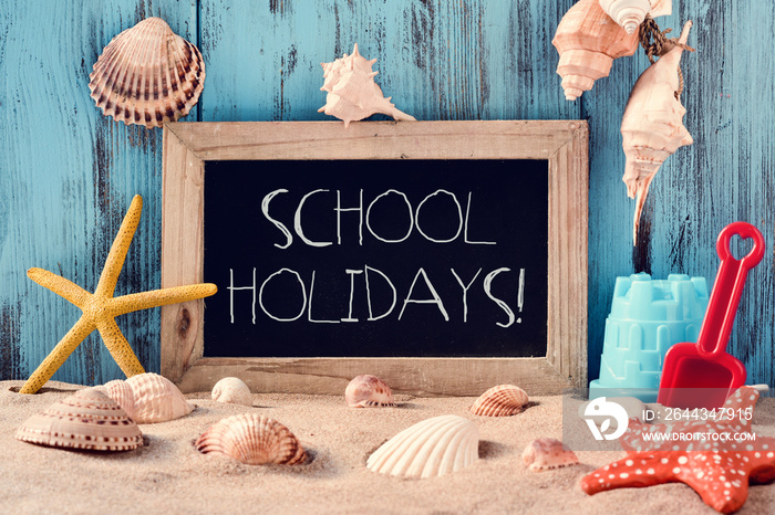 beach toys, seashells, starfishes and text school holidays