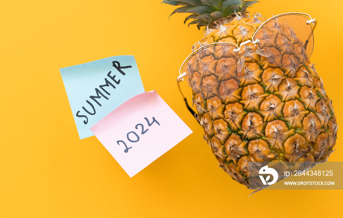 Funny pineapple with sunglasses and word summer 2024 on yellow background