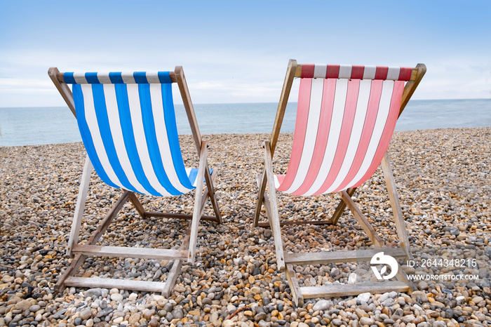 Deckchairs on beach, typical english seaside holiday scene, red and blue stripes representing main political party of labour or conservative