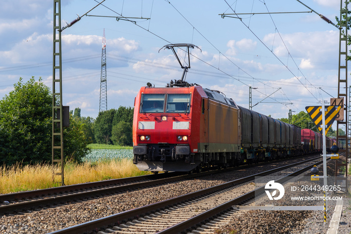 Outdoor sunny view of red locomotive  container train or railway freight transportation service, on the countryside in Germany.