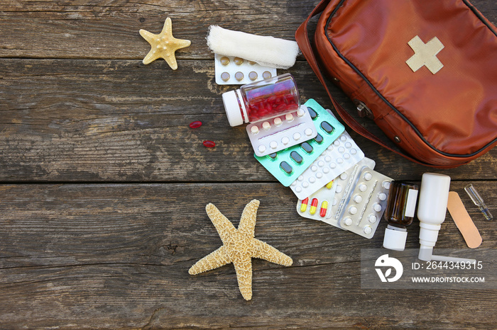 First aid kit on old wooden background. Concept of medication required in journey. Top view. Flat lay.