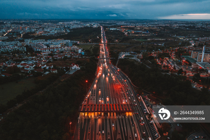 Aerial night view of the traffic road with cars passing through the point of toll highway, toll station. Amazing landscape of highway interchange in Portugal, Europe.