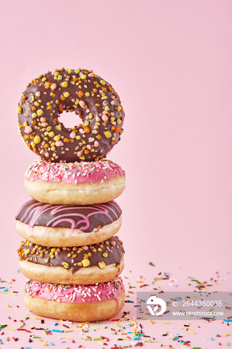 Stack of colorful donuts decorated on a pink background