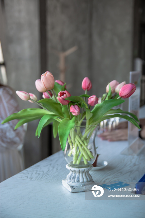 Bouquet of pink tulip in vase of glass. Decoration of dining table.