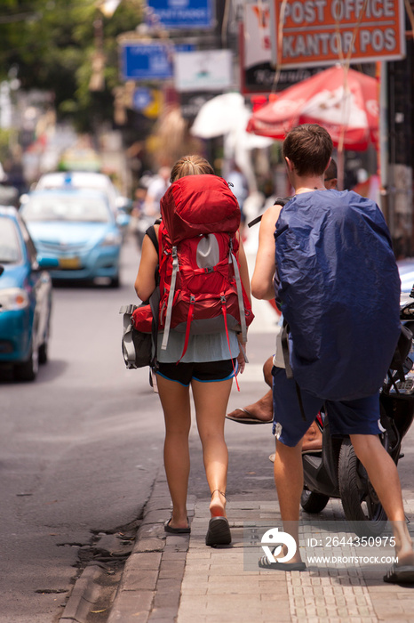 Two backpackers walk a busy street.