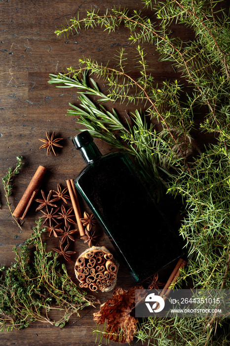 Vintage bottle, herbs, and spices on an old wooden table.