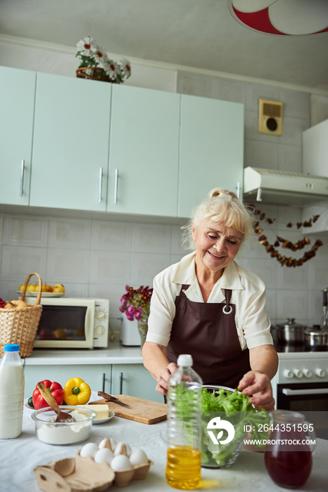 Lovely old lady cooking dinner in kitchen at home