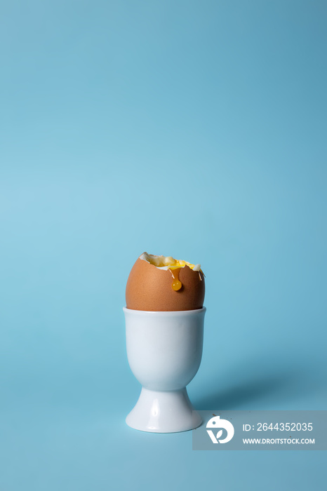 Soft boiled egg in egg cup on blue background