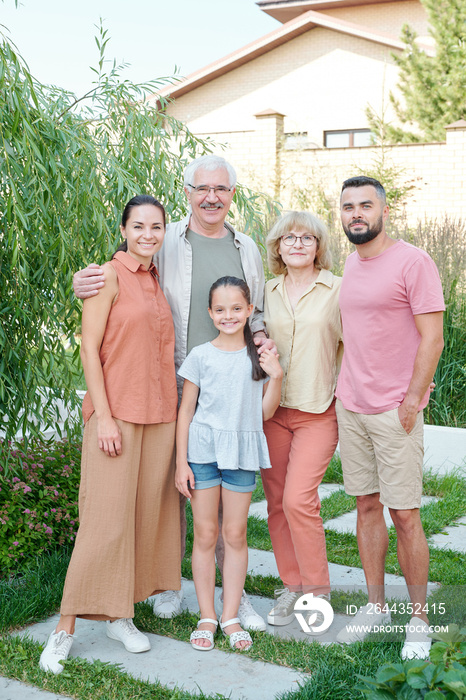 Big family of five standing together in modern park looking at camera smiling