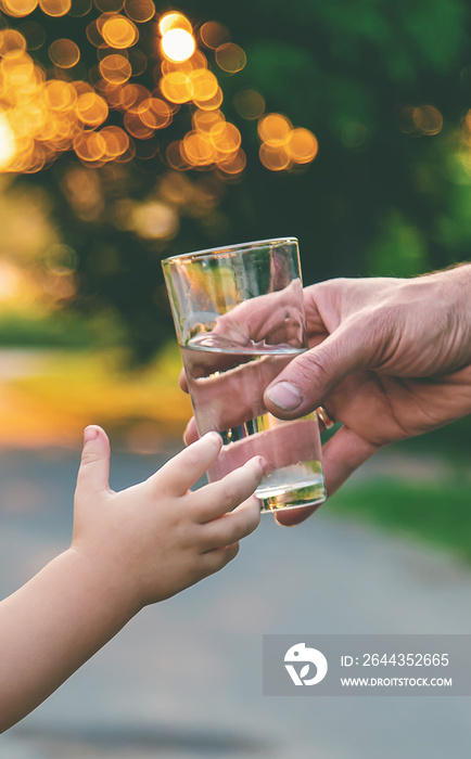 The child drinks water from a glass. Selective focus.