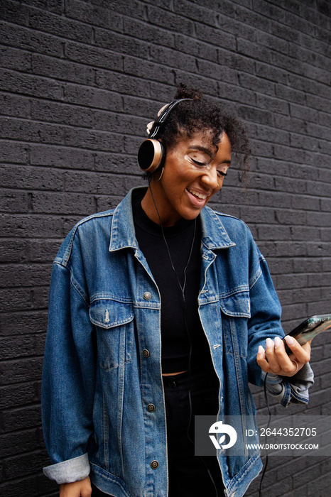 Curvy mixed-race woman with vitiligo taking a selfie in front of a black wall