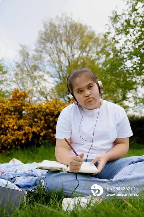 Young mid-sized woman with Down Syndrome listening to music in the park