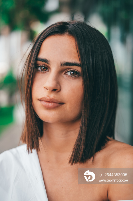 Happy young fashionable woman with short hair looking at camera outdoors. Beautiful satisfied lady with short hair smiling while facing camera. Portrait of confident female youth smiling.