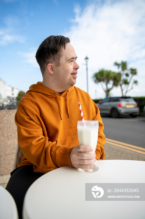 Man drinking milkshake in sidewalk cafe