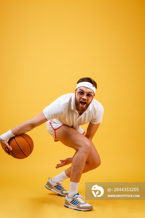 Vertical image of bearded sportsman in sunglasses playing basketball