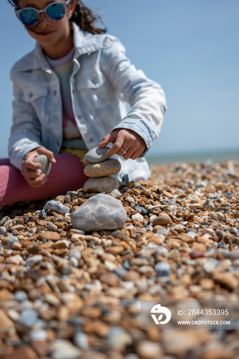 Girl (8-9) stacking stones on beach