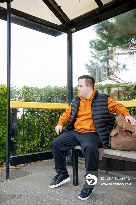 Man sitting on bench at bus stop