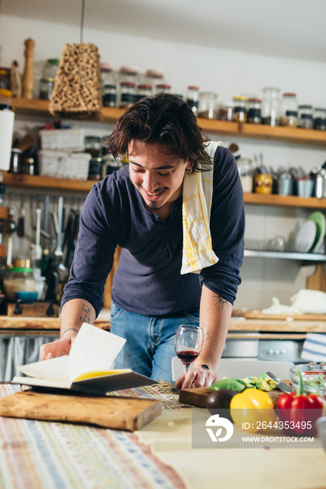 man looking for recipe in cook book in kitchen