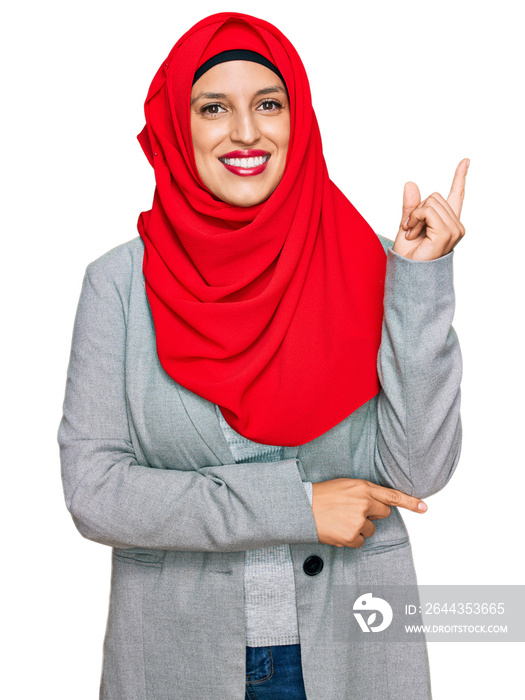 Beautiful hispanic woman wearing traditional islamic hijab scarf smiling happy pointing with hand and finger to the side