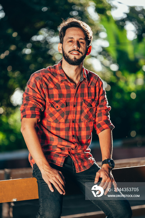 Young handsome man sitting on fence at a farm