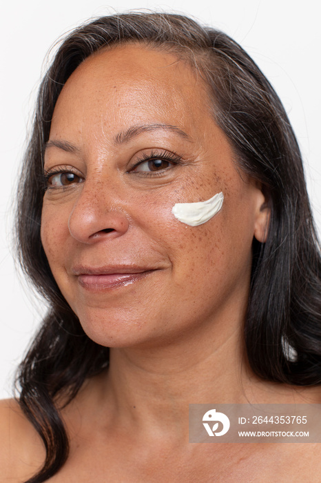 Studio portrait of smiling woman with face cream on cheek