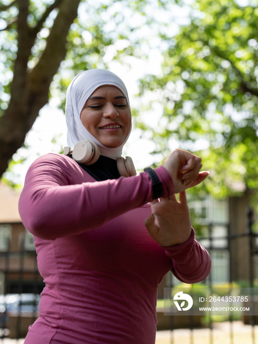 UK,Sutton,Smiling woman in headscarf checking smart watch