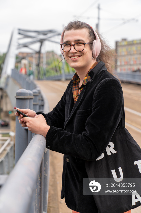 Portrait of smiling man listening music on city street