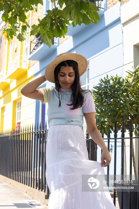 Smiling young woman in sun hat standing in street