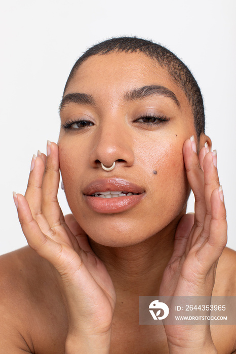 Studio portrait of woman with nose ring touching face