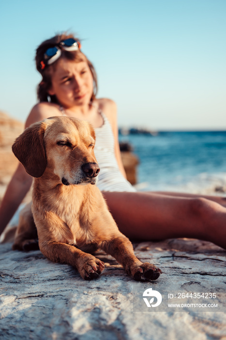 Dog and girl lying down on the beach