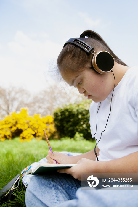 Young mid-sized woman with Down Syndrome listening to music in the park