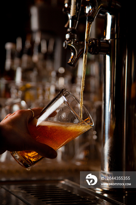 Beer pouring into tilted pint glass at brewery bar