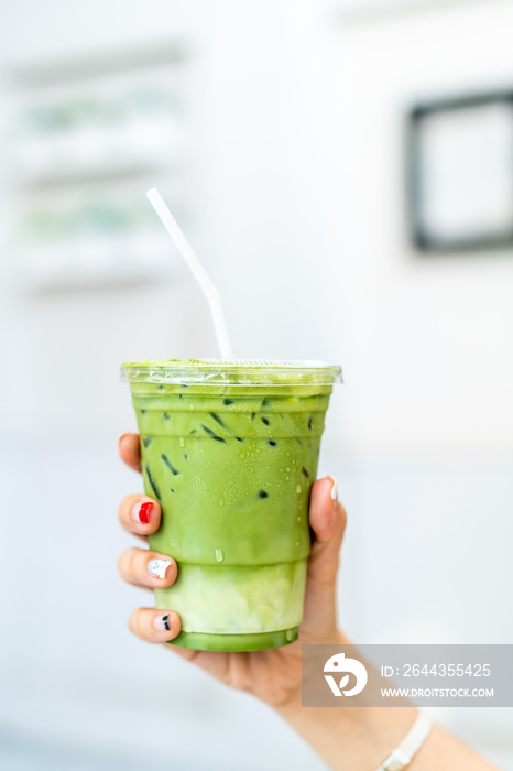 hand holding iced matcha latte green tea cup