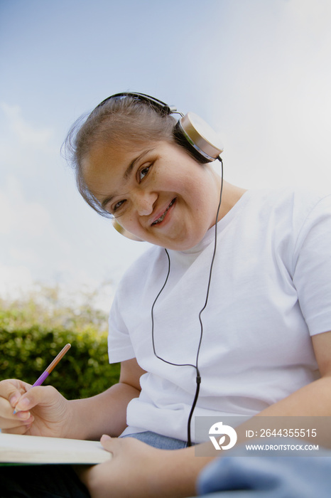 Young mid-sized woman with Down Syndrome listening to music in the park