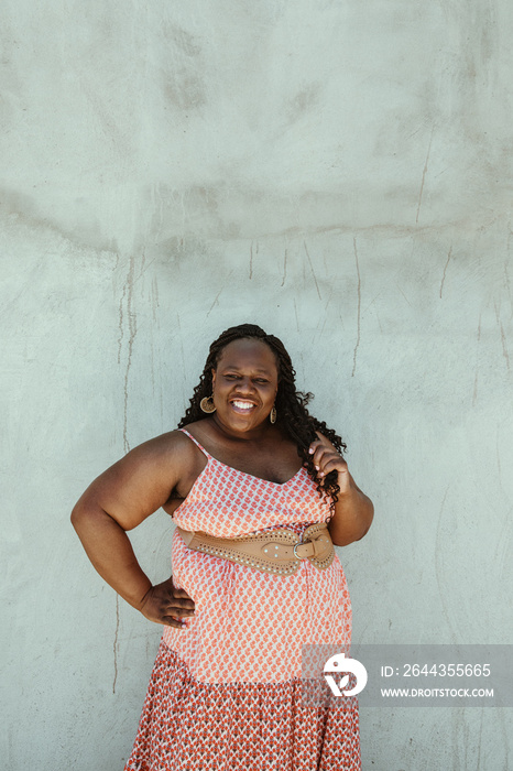 plus size African American woman smiling at camera against a textured wall