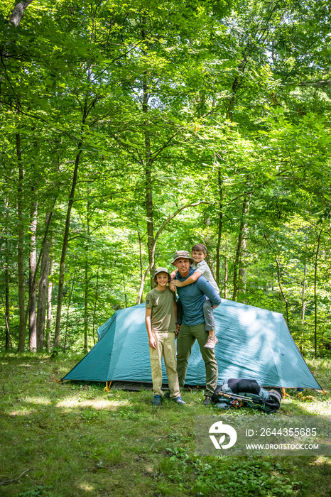 Air Force service member sets up a tent with his sons on  a backpacking trip.