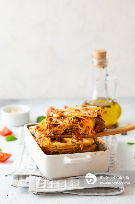 Traditional italian lasagna with vegetables, basil, minced beef meat, tomato and cheese on concrete background.