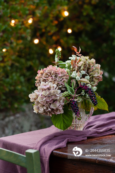 Beautiful hydrangea bouquet on a wooden table. Lights on background