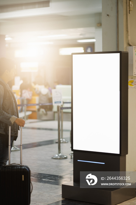 traveller man looking blank advertising billboard at airport.