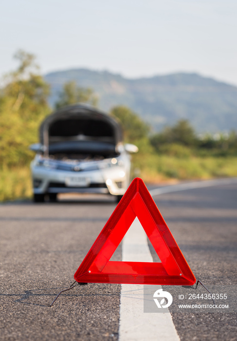 Red emergency stop sign and broken car on the road