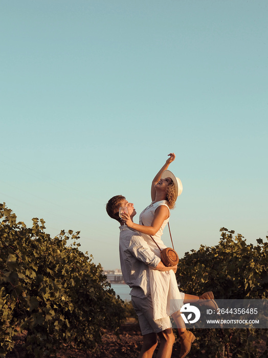 Couple with glasses drinks wine in vineyard