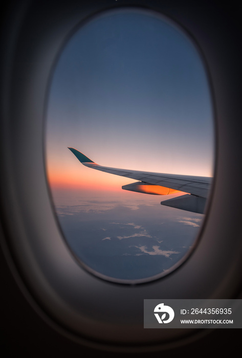 Silhouette wing of an airplane at sunrise view through the window.