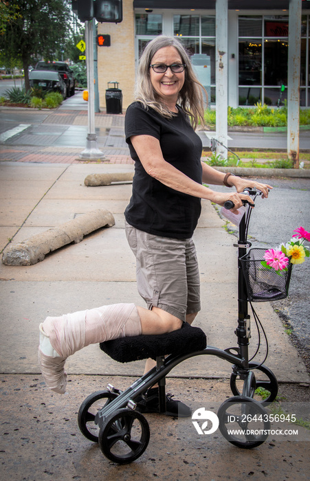 Woman on mobility scooter on street with leg wrapped smiling at camera