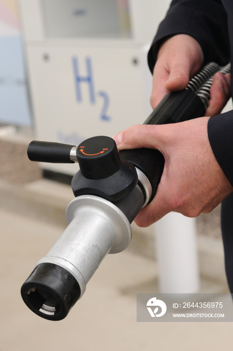 Man holding a hydrogen fuel filler nozzle for refueling hydrogen powered vehicles