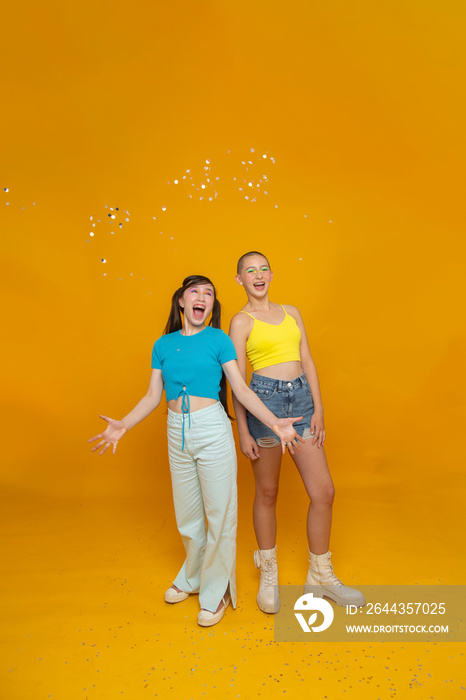 Studio portrait of smiling stylish friends with confetti