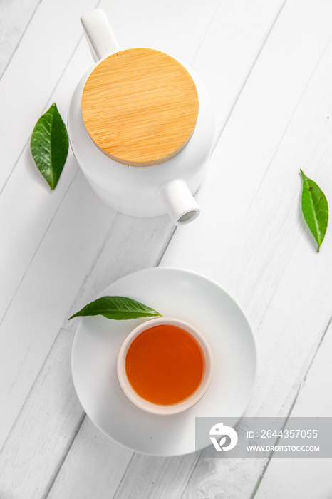 top view or flatlay with herbal tea in a cup and teapot on white wooden background, teatime ceremony, traditional chinese or japanese tea. High quality photo