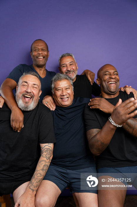 Portrait of smiling men in black t-shirts against purple background