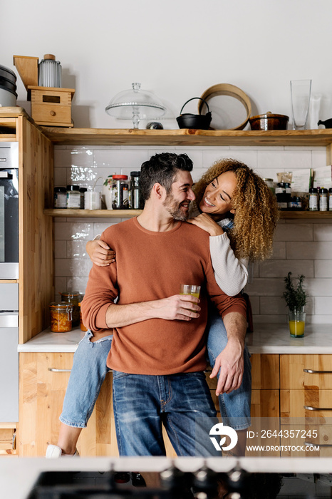 Couple laughing and standing in kitchen.